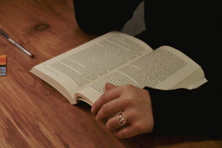 A person reads an open book on a wooden table indoors in Bursa.